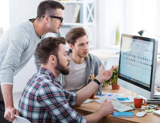 Three business people discussing something together while looking at the monitor