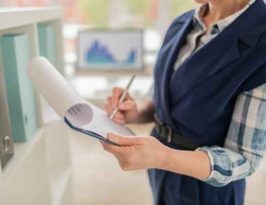 a woman standing in an office, holding a tablet with documents in her hands